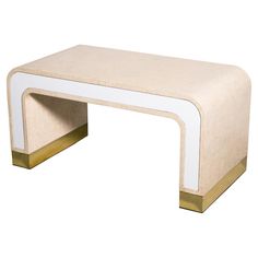 a white and gold coffee table with an open shelf on the bottom, in front of a white background