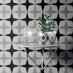 a table with two vases on it next to a black and white wallpaper