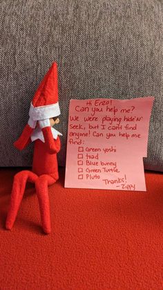 an elf is sitting on the floor next to a note