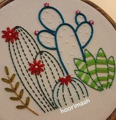 a close up of a embroidery on a piece of cloth with flowers and cactuses