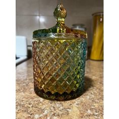 a green glass jar sitting on top of a counter next to a yellow canister