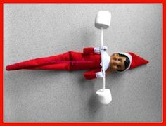 an elf is laying on the floor with a toothbrush in his mouth and wearing a red suit