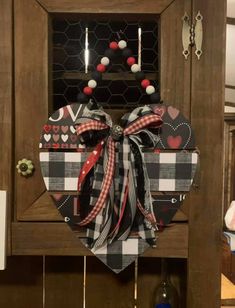 a wooden cabinet with a bow hanging from it's front door, decorated with hearts and other decorations