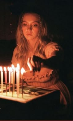 a woman sitting in front of a cake with lit candles