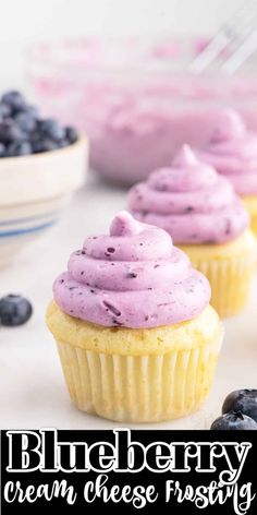 three blueberry cream cheese frosting cupcakes with fresh blueberries in the background