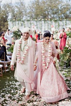 a man and woman are walking down the aisle with flowers all around their necks