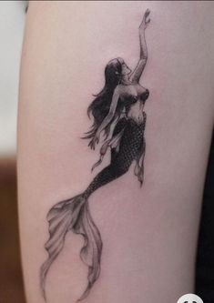 a woman with a mermaid tattoo on her thigh is holding onto the tail of a fish