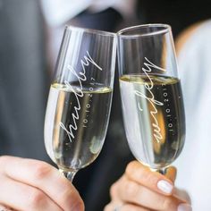 two people holding up wine glasses with writing on them