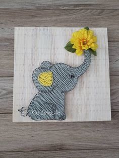 an elephant with a yellow flower in its trunk on a wooden background that says welcome home