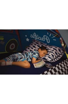 a young boy laying in bed reading a book