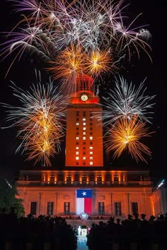 fireworks are lit up in the night sky above a building with a clock tower on top