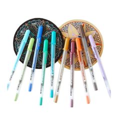 several pens are lined up in front of a plate with an ornament on it