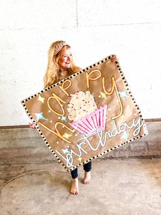 a woman holding up a happy birthday sign with cupcakes and stars on it