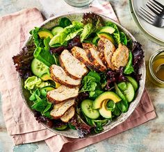 a salad with chicken, lettuce and cucumbers