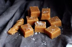 several pieces of caramel fudge sitting on top of a black cloth covered in sea salt