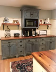 a kitchen with gray cabinets and wood floors, including a microwave oven above the counter