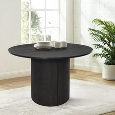 a black table with two white plates on it in front of a potted plant