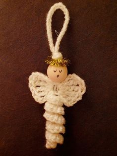 an angel ornament hanging on a brown surface with a white string attached to it