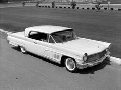 black and white photo of an old car parked on the side of the road with grass in the background