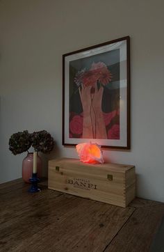 a wooden table topped with a vase filled with flowers and a painting on the wall