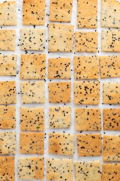 crackers with black sesame seeds are arranged on a sheet of parchment paper, ready to be cut into squares