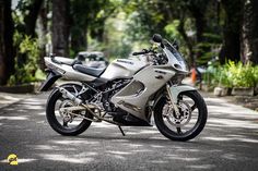 a silver motorcycle parked on the side of a road next to some trees and bushes