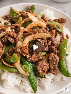 a white plate topped with beef and onions on top of rice covered in seasoning