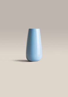 a light blue vase sitting on top of a table next to a white wall and floor