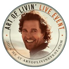 a man with long hair smiling and wearing a white t - shirt in front of a round sign that says art of livin's live event