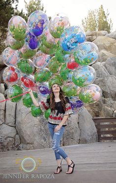 a woman is posing with balloons in her hands