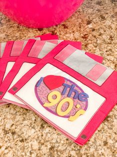 pink and white napkins with the number 90 on them sitting on a counter top