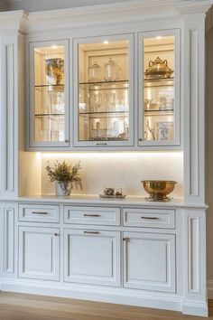 Elegant white kitchen cabinet displaying glassware and silverware with built-in lighting. Glass Door Cabinet Kitchen, Glass Cabinet With Light, Glass Cabinet Light, Glass Cabinets With Lights, Kitchen Clear Cabinets, Kitchen Cabnit With Glass Doors, China Cabinet Lighting, Clear Cabinets Kitchen, Light Cabinets Kitchen