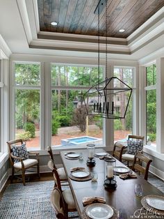 a dining room table with plates and place settings in front of large windows overlooking a pool