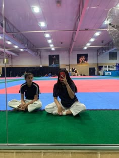 two people sitting on the ground in front of a mirror