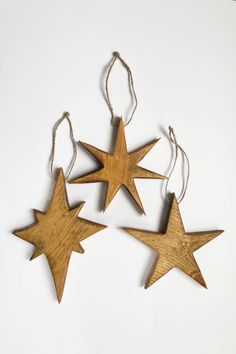 three wooden stars hanging from strings on a white surface