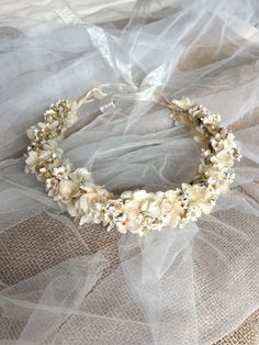 a white flower crown on top of a bed covered in tulle and sheer fabric