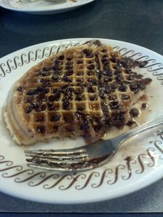 a white plate topped with waffles on top of a table next to a fork