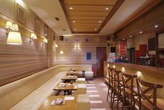 an empty restaurant with wooden booths and lights on the wall, along with long tables