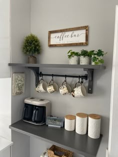 a coffee bar with cups and mugs on the shelf next to it is decorated with potted plants