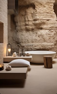 a bath room with a large stone wall and a white tub next to a sink