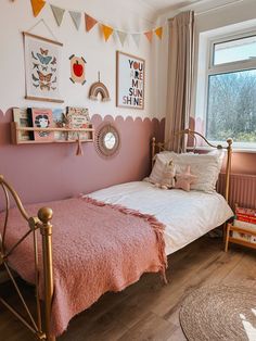 a bedroom with pink walls and wooden flooring is decorated in pastel colors, including gold