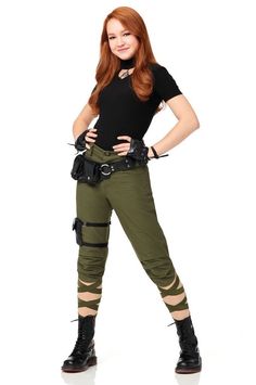 a woman in green pants and black shirt posing for the camera with her hands on her hips