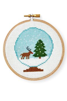 a cross stitch pattern with a deer and tree in the snow on a white background