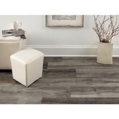 a white chair sitting next to a vase with flowers in it on top of a wooden floor