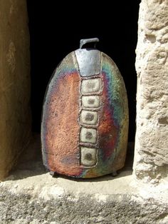 a colorful vase sitting on top of a stone window sill