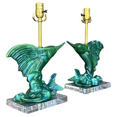 a pair of green glass table lamps on marble bases with gold colored candlesticks