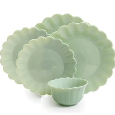 the green dishes are stacked on top of each other, and have ruffled rims