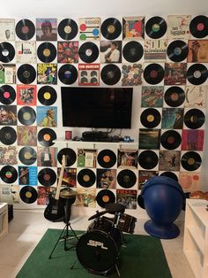 a room with various records on the wall and a drum set in front of it