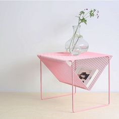 a pink side table with a vase on it and a magazine in front of it