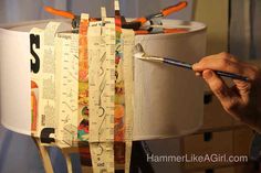 a person holding a paintbrush and drawing on a piece of paper that is attached to a lamp shade